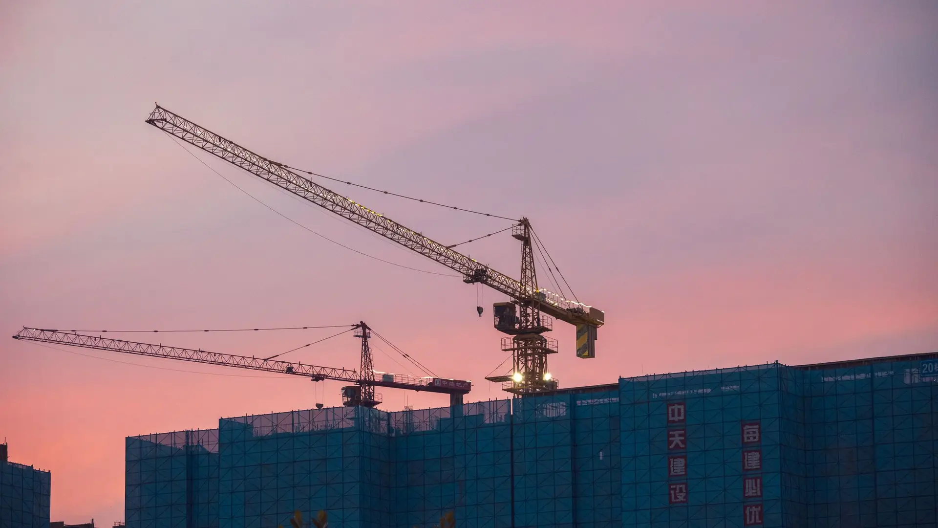 Grúa torre sobre una obra en construcción al atardecer